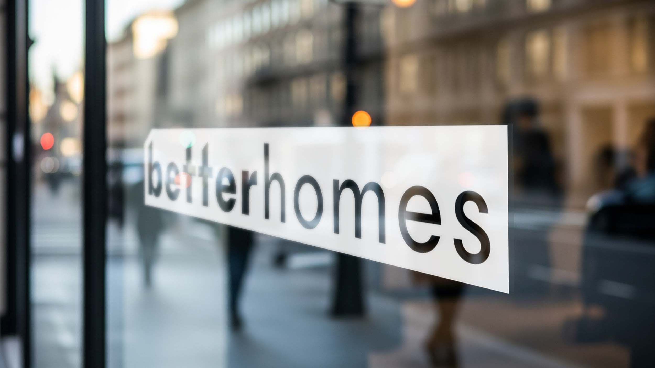 Frau im Anzug vor einem Gebäude telefoniert mit BETTERHOMIE