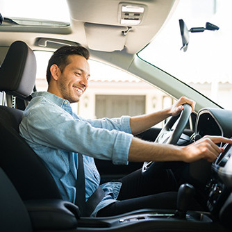 Junger Mann in einem Auto stellt den Radio ein